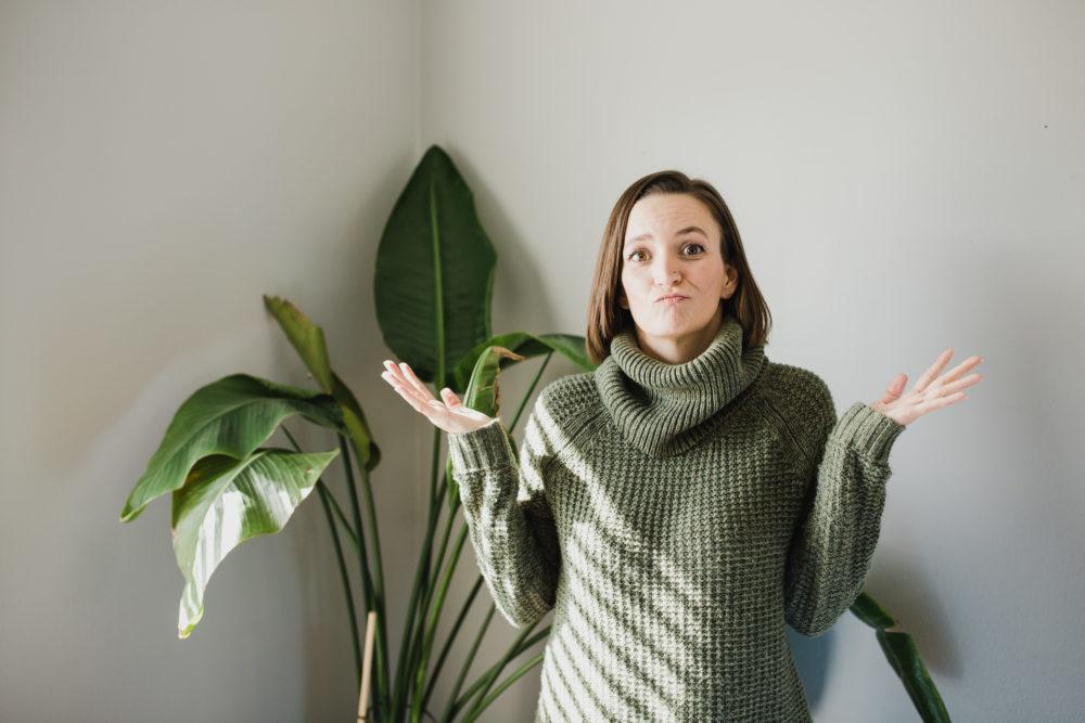 Tara wearing green sweater with hands up in uncertainty