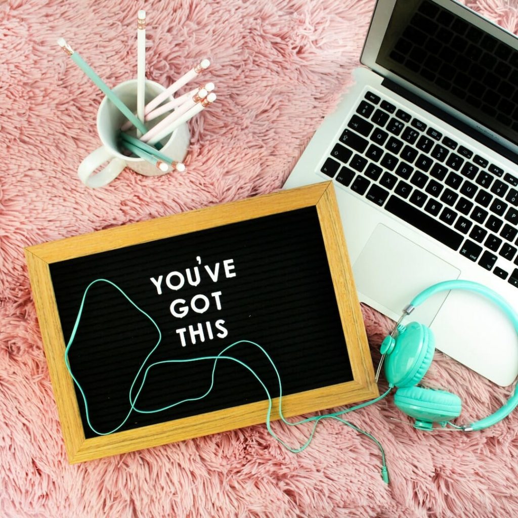 Letterboard that says you've got this" on pink carpet beside blue headphones