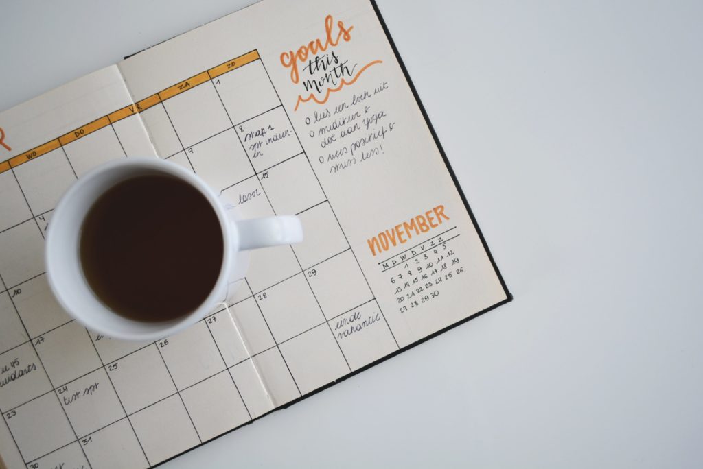 cup of coffee sitting on a monthly planner