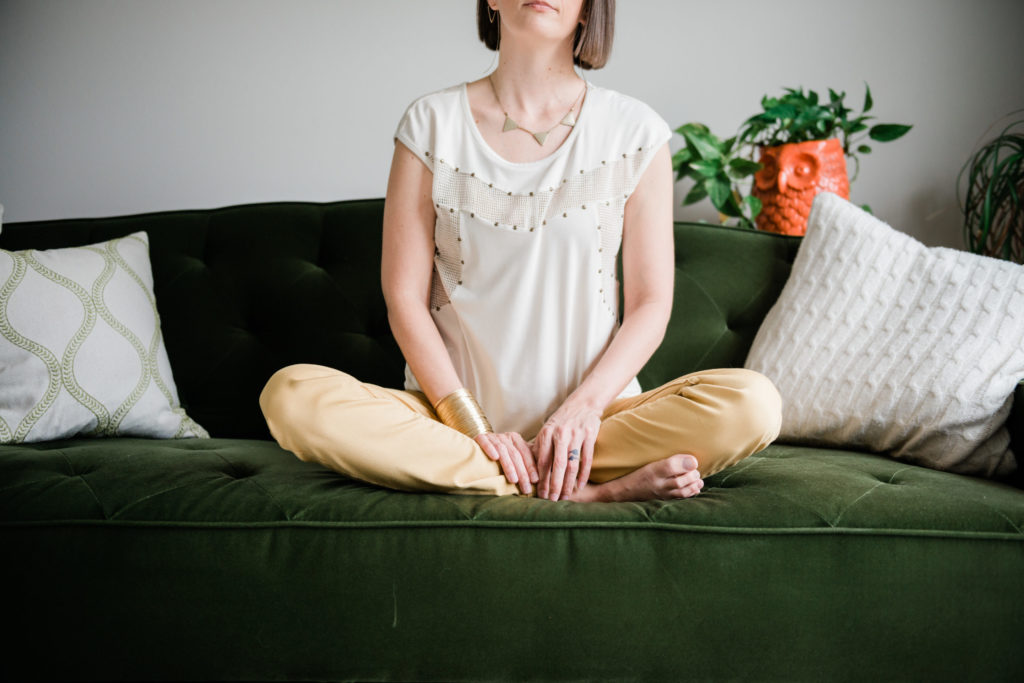 Tara in meditation pose on pin-tucked emerald couch