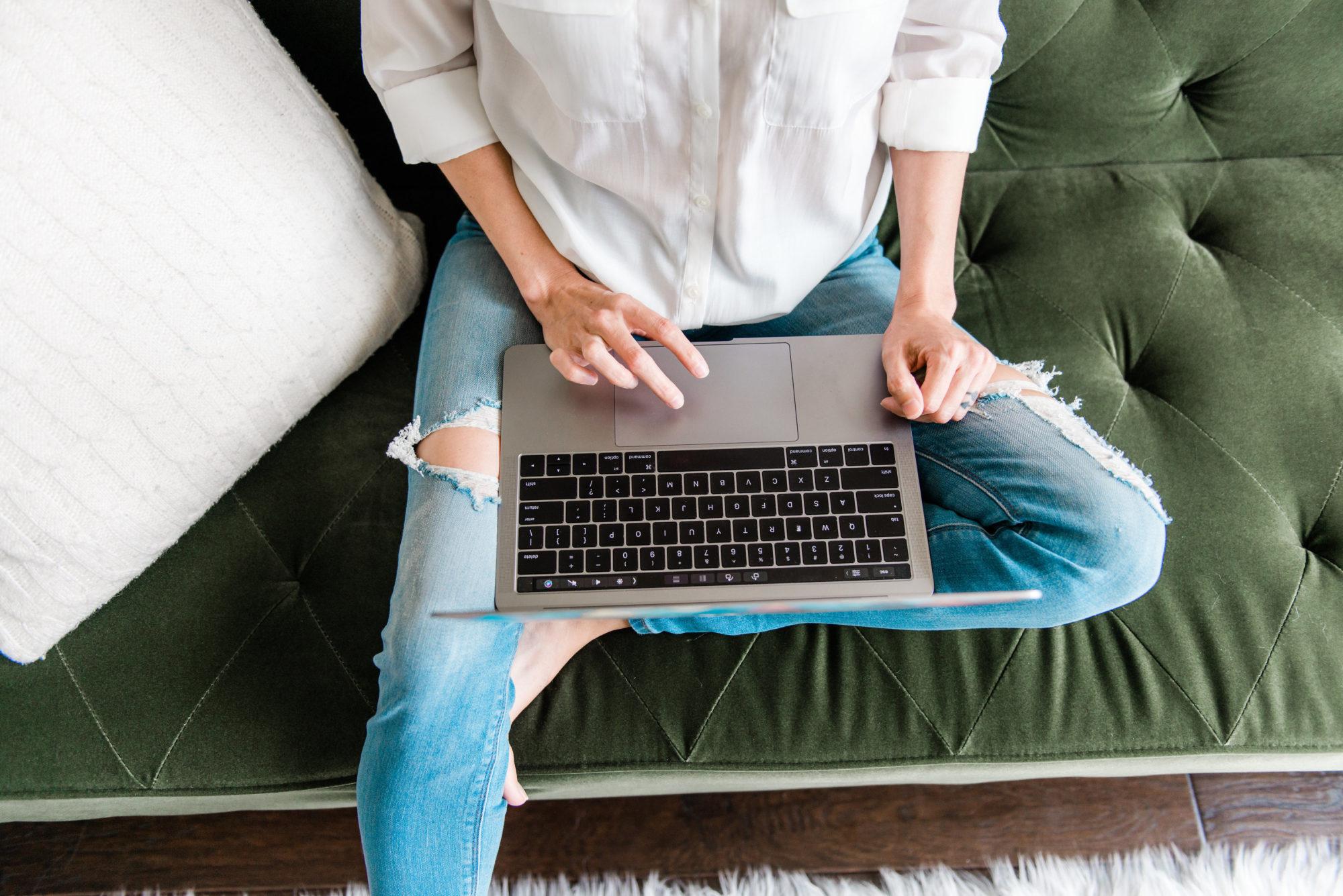 overhead of Tara on her lap top wear jeans and a white shirt