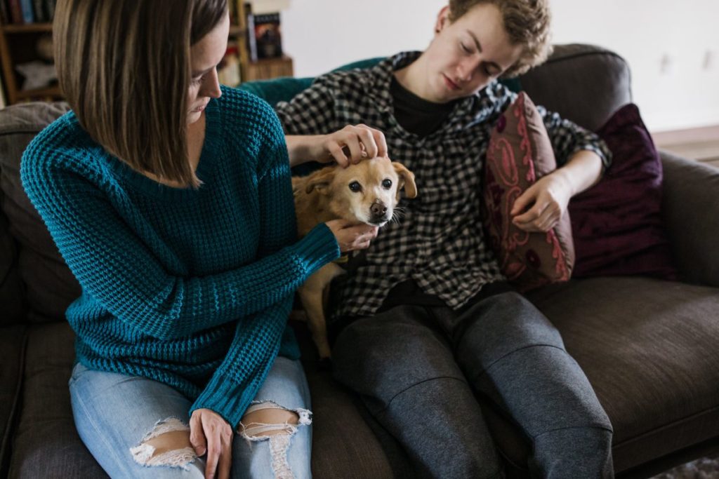 Tara and Zeb petting their dog together on the couch