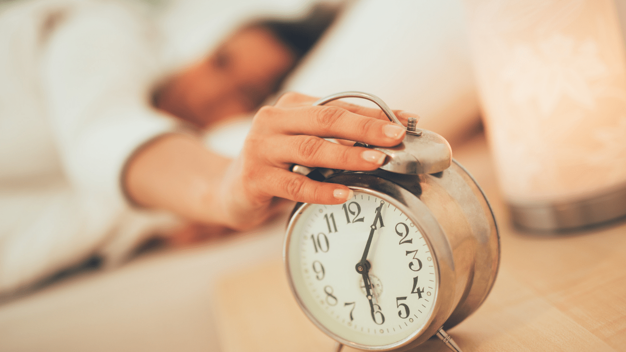 Woman's hand reaching over and turning off the alarm clock