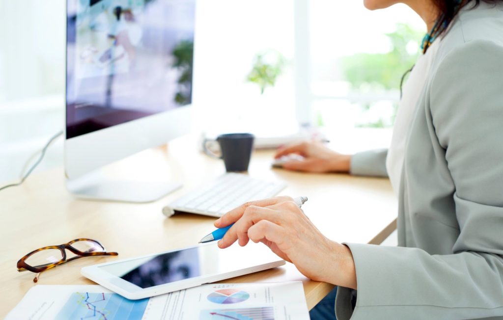 Woman working at computer desk with pen in hand