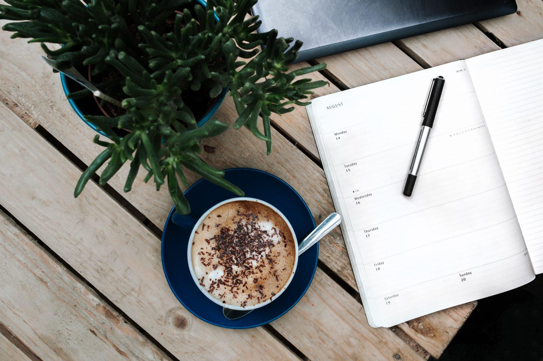 top view of a coffee, notebook and paper and plant