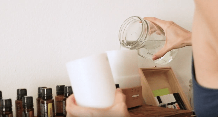 Tara filling up a diffuser with water beside multiple bottles of essential oil