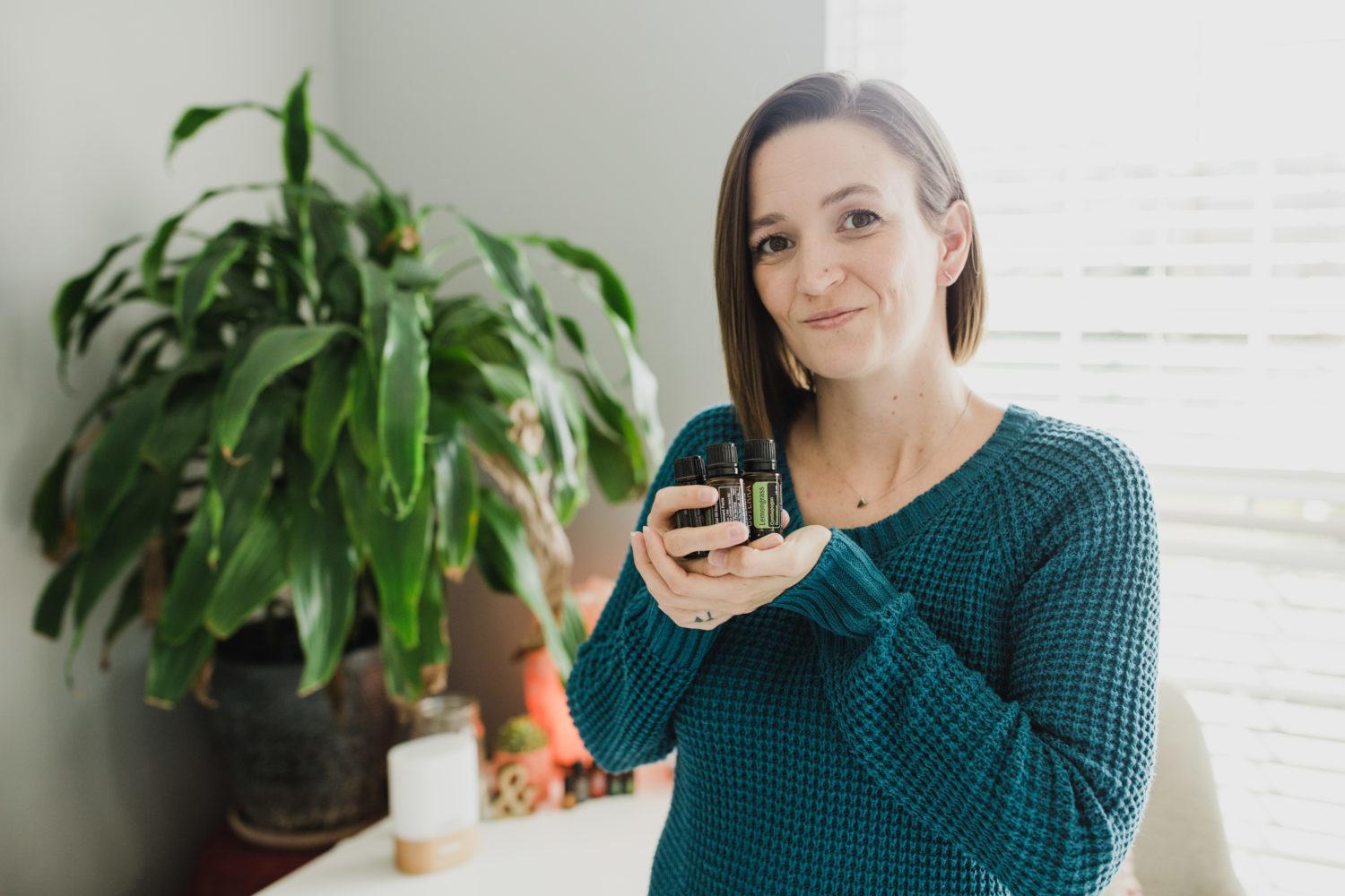 Tara holding essential oil bottles in the palm of her hand confidently smiling