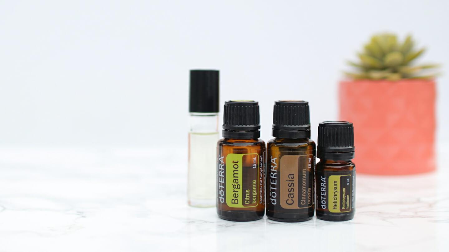 Bergamot, Cassia, and Helichrysum essential oils with carrier oil rollerball on white background and tabletop