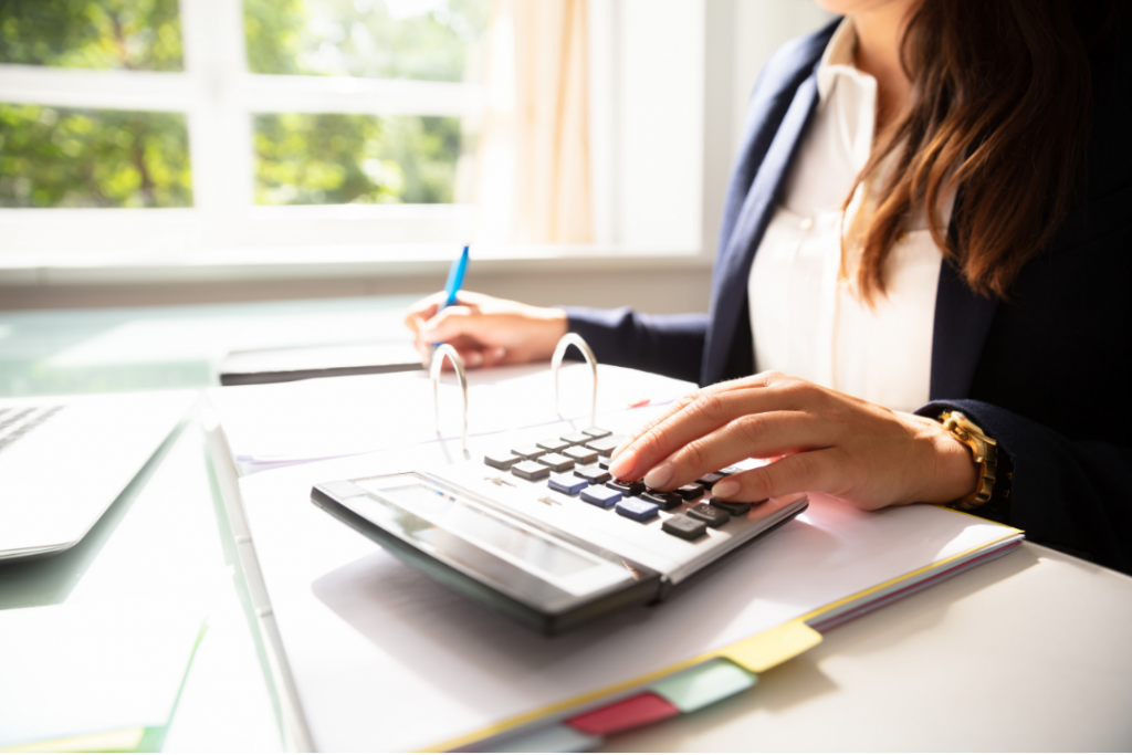 Business woman using a calculator and writing