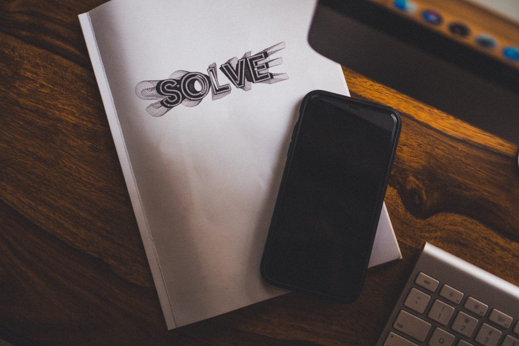 Black phone on top of white notebook that says "solve".