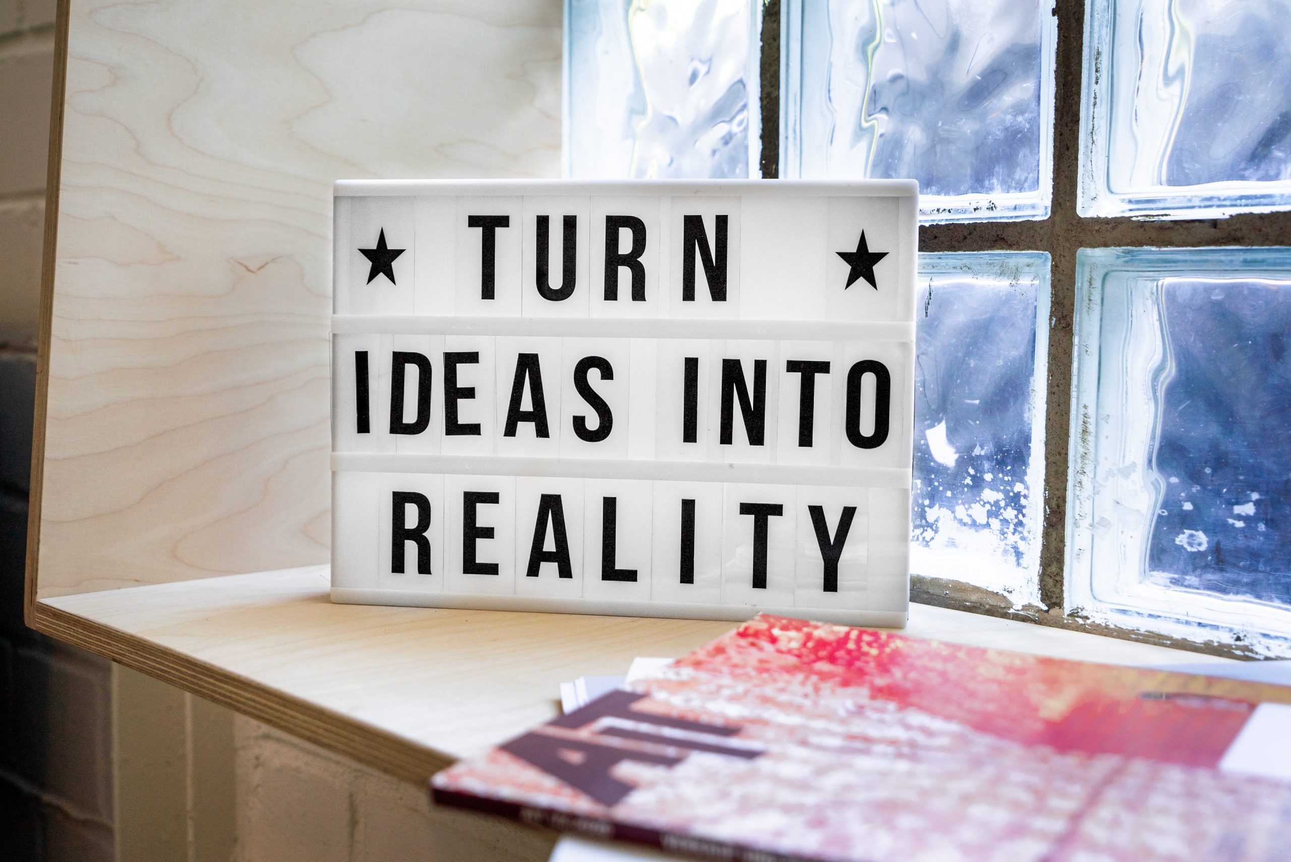A sign sitting on a desk saying turn ideas into reality