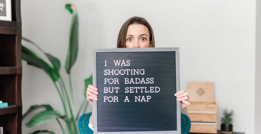 Tara holding a sign that says "I was shooting for badass, but settled for a nap"