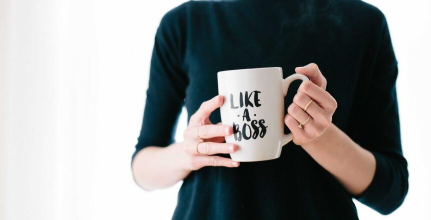 Woman in black 3/4 sleeve shirt holding a white mug that says "LIKE A BOSS".