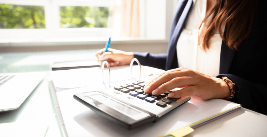 Business woman using a calculator and writing