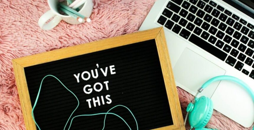 Letterboard that says you've got this" on pink carpet beside blue headphones