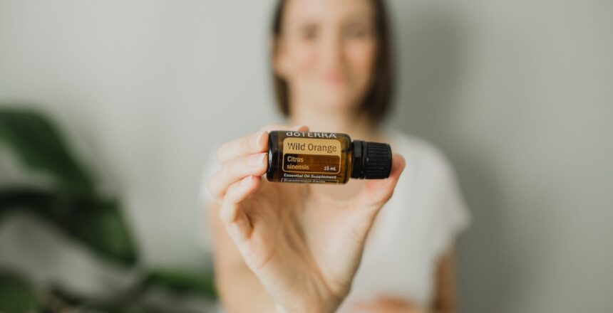 Tara out of focus holding Wild Orange essential oil bottle focused