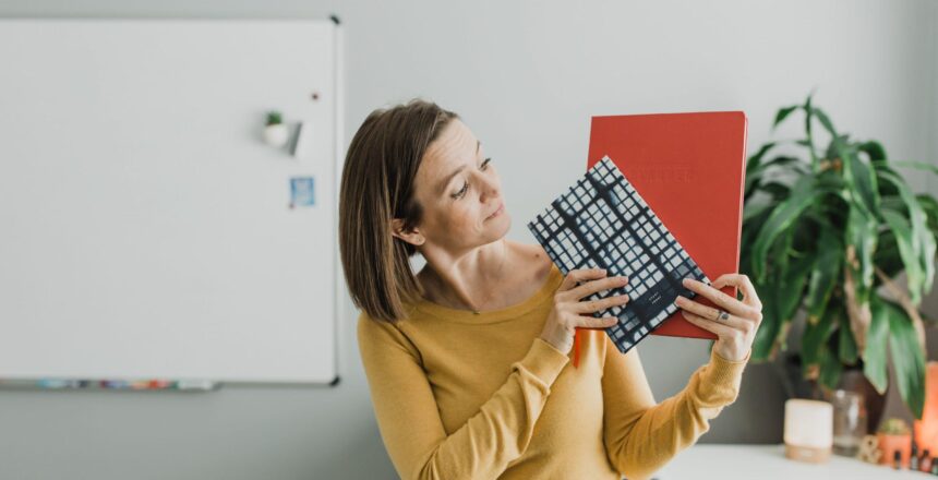 Tara in mustard long-sleeve shirt in office holding up 2 planners