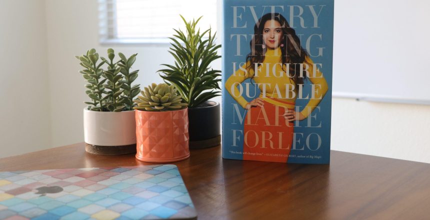 Marie Forelo's book Everything is Figureoutable sitting on desk beside plants and laptop