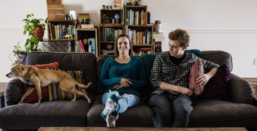 Tara sitting on the couch with Zeb laughing in their living room