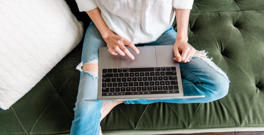 overhead of Tara on her lap top wear jeans and a white shirt