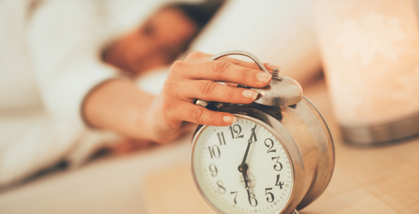 Woman's hand reaching over and turning off the alarm clock