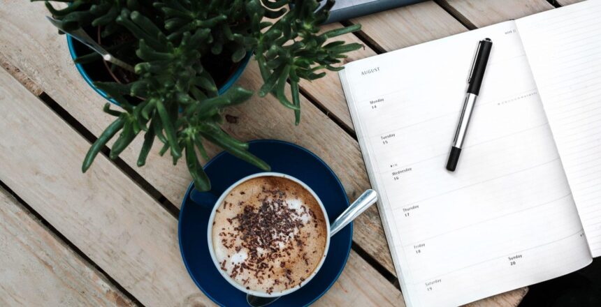 top view of a coffee, notebook and paper and plant