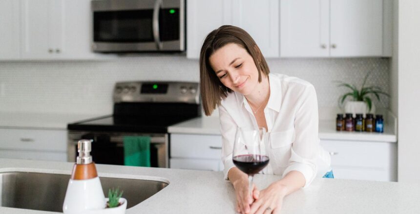 Tara smiling with a glass of wine in her kitchen