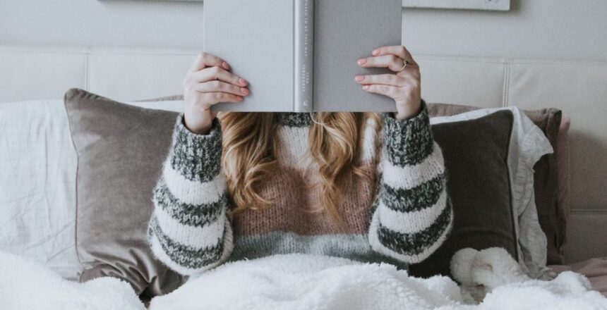 Woman sitting in bed with a book in her hands reading intently