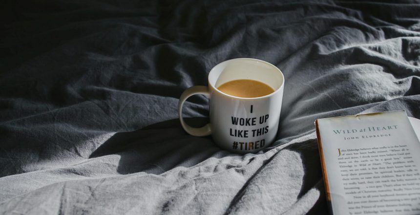 Coffee cup on bed with quote "i woke up like this #tired"