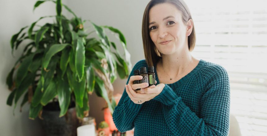 Tara holding essential oil bottles in the palm of her hand confidently smiling