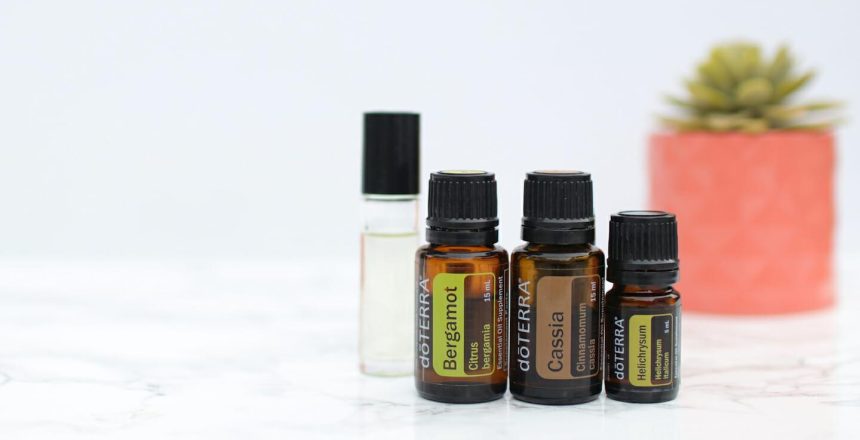 Bergamot, Cassia, and Helichrysum essential oils with carrier oil rollerball on white background and tabletop