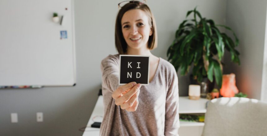 Tara holding u a sign that says "kind"