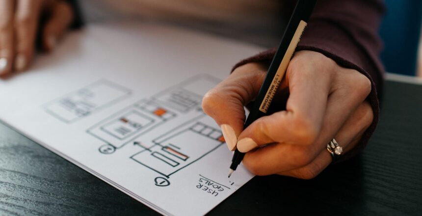 A photograph of a female holding a pen and writing down her goals on paper