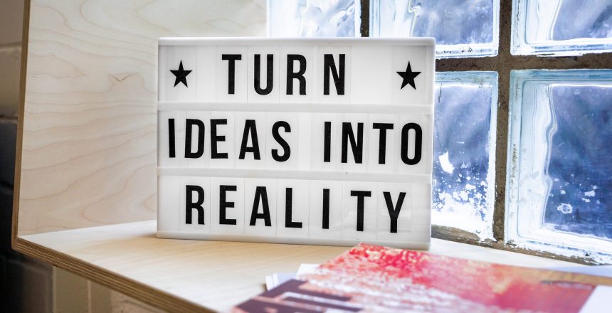 A sign sitting on a desk saying turn ideas into reality