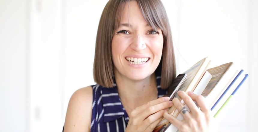 Tara hold a stack of money mindset books smiling